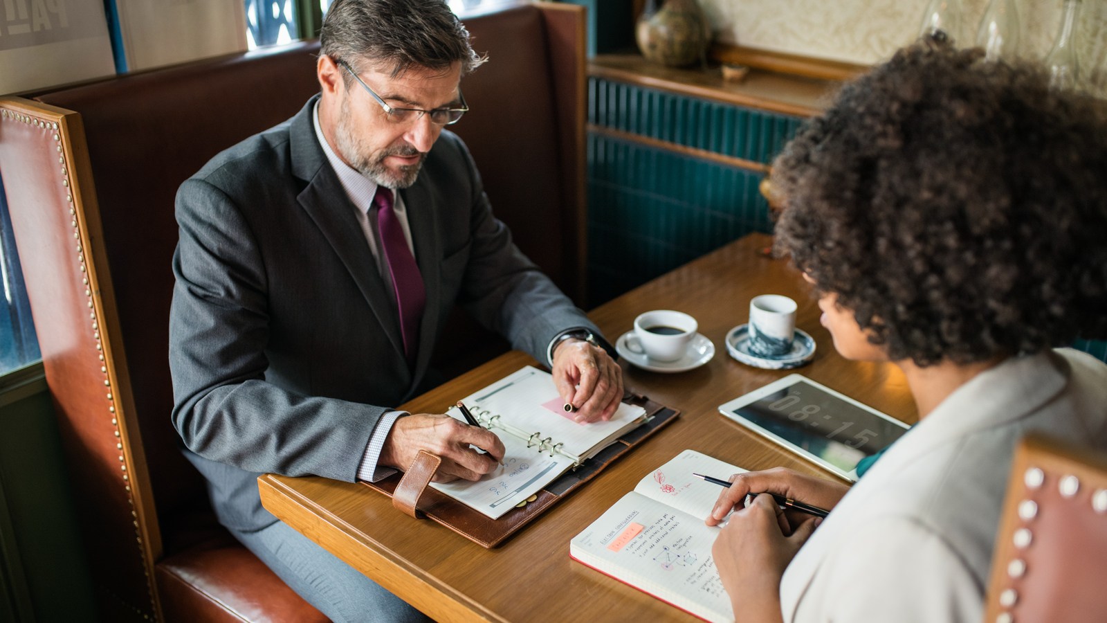 Duas pessoas revisando números em uma reunião de trabalho
